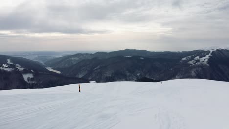 Snowy-Iezer-Papusa-Mountains-with-Rausor-Dam-in-the-distance,-overcast-sky