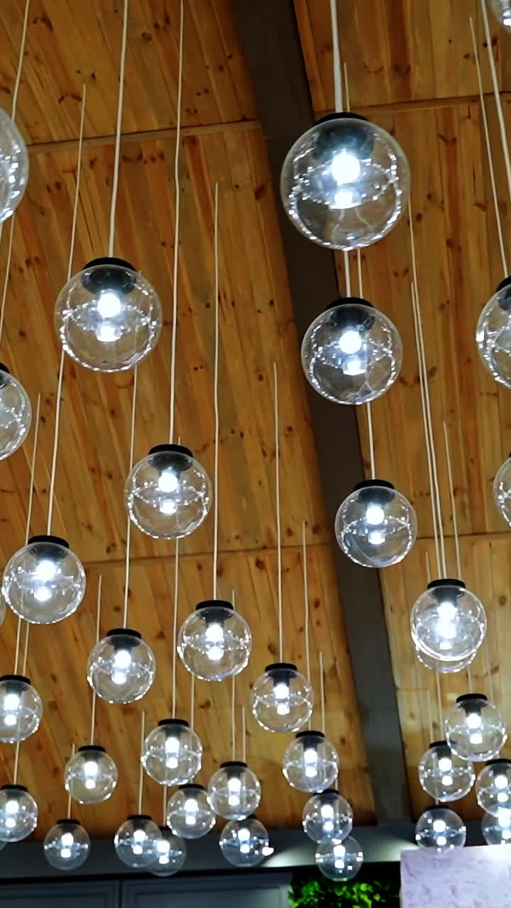 Creative interior of many lamps. Modern ceiling lighting of hanging light bulbs indoors. Vertical video