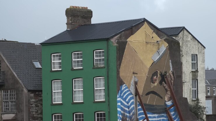 Gadekunst med trist ansigt på bygning i Cork