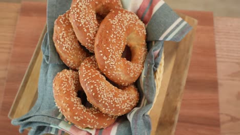 sesame seed covered bagels on towel in woven basket, top view, turning