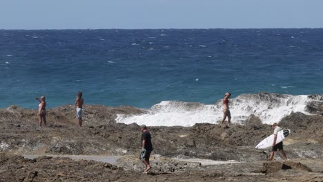 group of surfers entering ocean from rocky coast