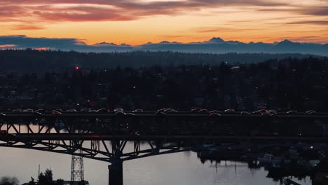 cars drive across the i5 highway bridge in seattle over lake union while the sun sets behind the olympic mountains