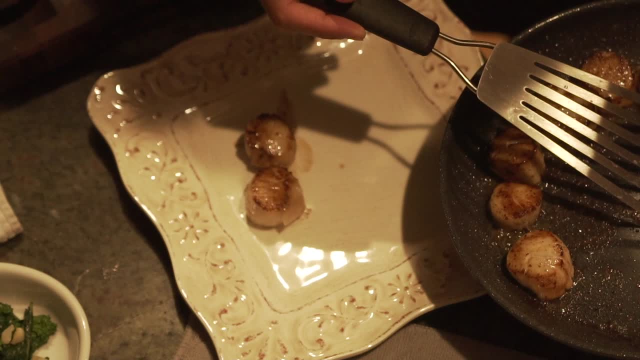 Slow motion shot of grilled sea scallops being plated in HD 1080p 23.98p