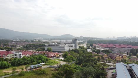 Vorbei-An-Bäumen-Fliegen-Geradewegs-Auf-Ein-Mini-Einkaufszentrum-Und-Wohngebiet-Mit-Tälern-Am-Horizont-In-Malaysia-Zu