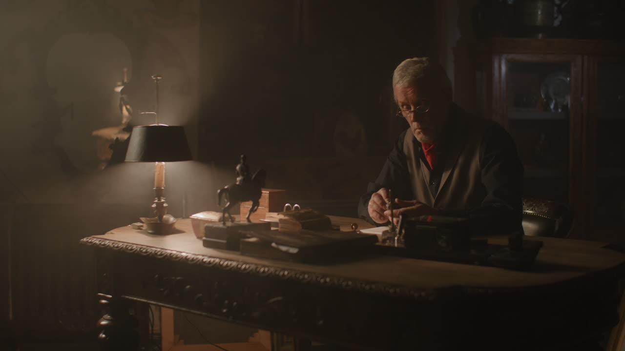 Older passionate man evaluates an old silver skull watch in his office at night