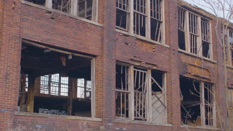 a red brick abandoned warehouse with broken windows and doors, industrial decay