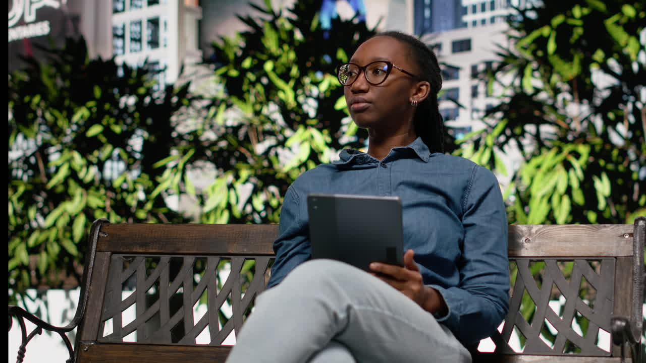 African american joyous girl using tablet to read e-books walking in city