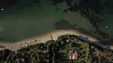 Flying-over-sea-coast-resort-Sunbeds-at-the-beach-and-villa-on-seafront