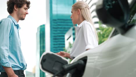 Progressive-businessman-and-businesswoman-use-charging-station-for-EV-car.