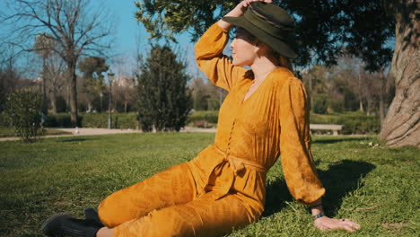 Stylish-young-woman-sitting-in-the-grass-outdoors.