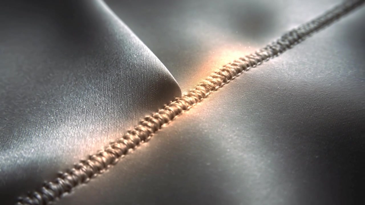 Pushing camera toward stitched seam in studio, revealing looped thread and satin sheen
