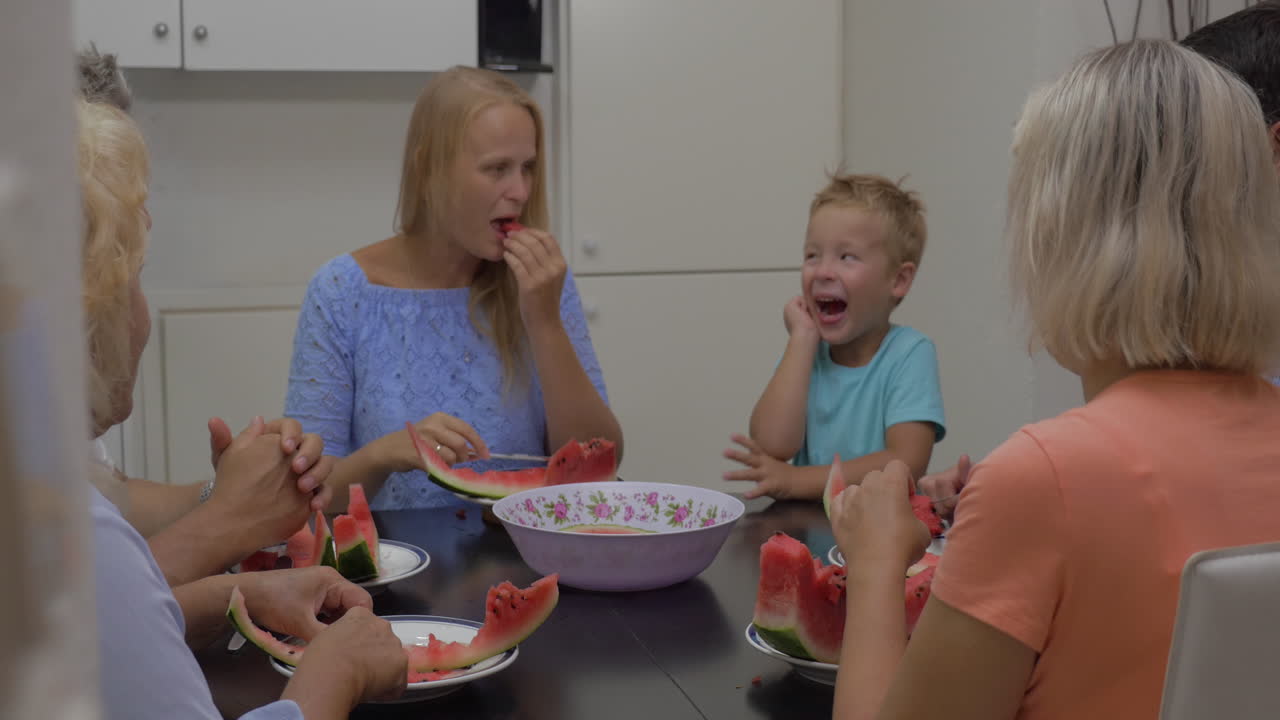 familia con un niño comiendo sandía en la cocina