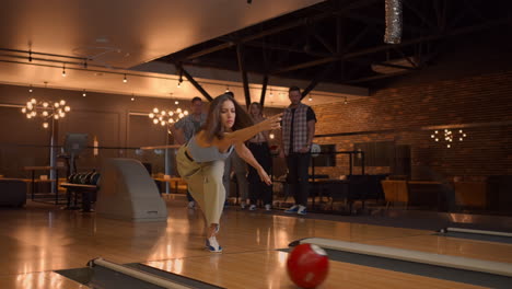 a woman makes a throw in a bowling club and enjoys emotionally knocking out pins with a ball