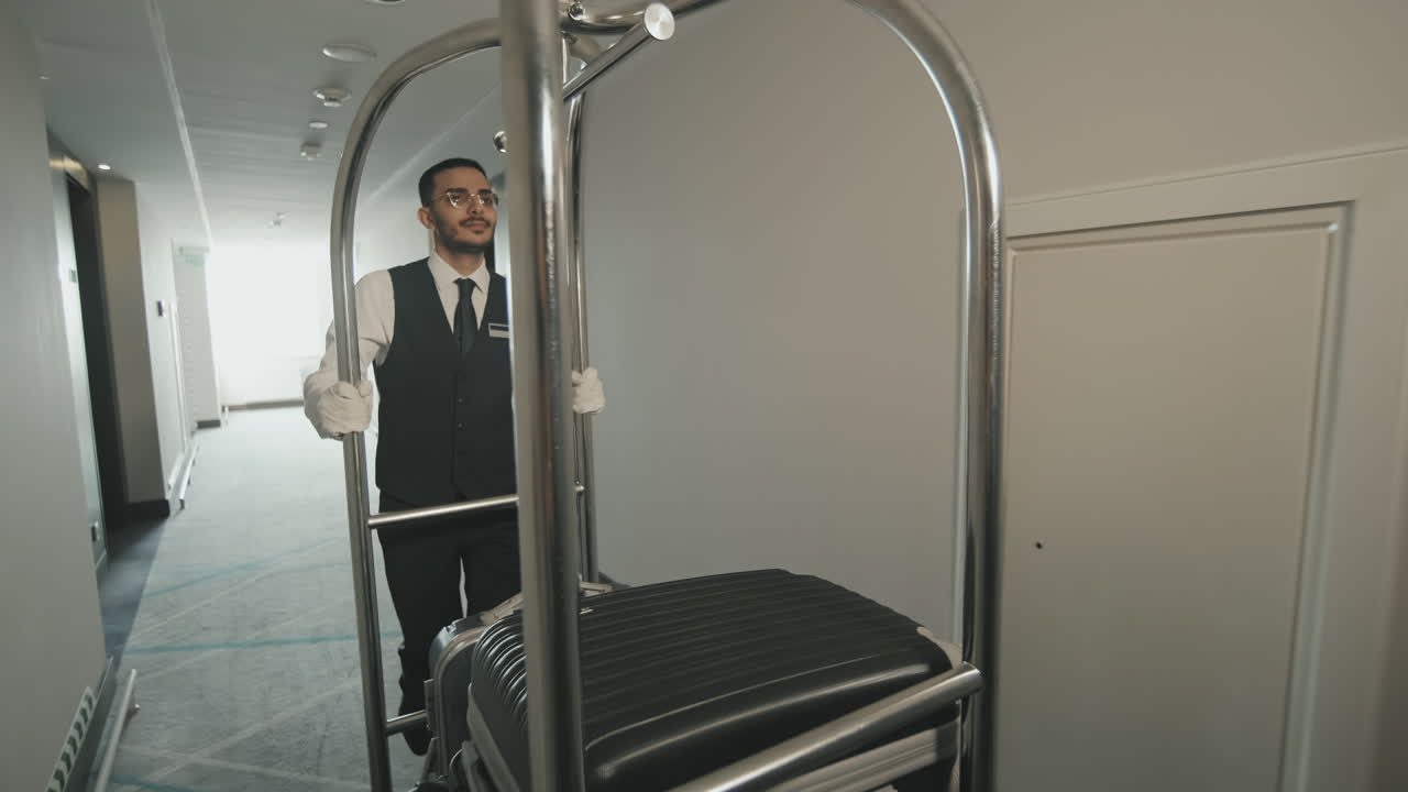 Porter with Baggage Cart Walking along Hotel Corridor