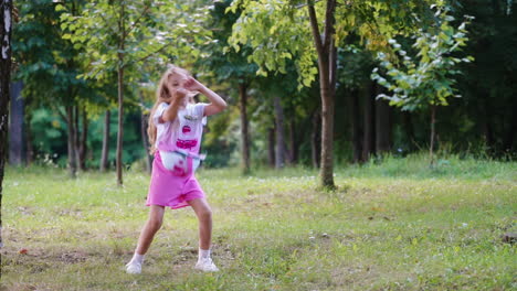 girl dancing outdoors in park. little blonde girl dancing in green park