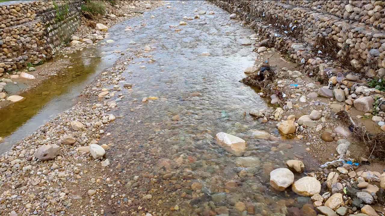agua de lluvia fresca que fluye a través de un arroyo sucio y rocoso seco durante la temporada de lluvias
