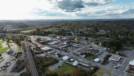 traffic on main street of small american town in autumn season.sunny day with clouds over forest landscape. tracks of railroad and bridge over river in background. virginia, america.aerial wide shot.