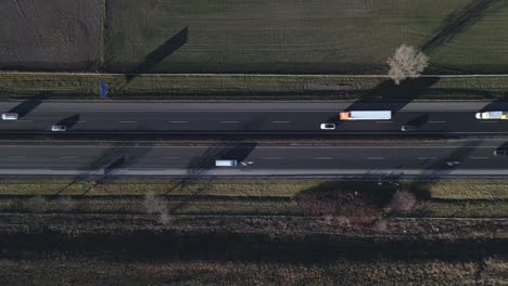 aerial top down video of highway with moving vehicles, including trucks, cars and buses while drone moves sideways.