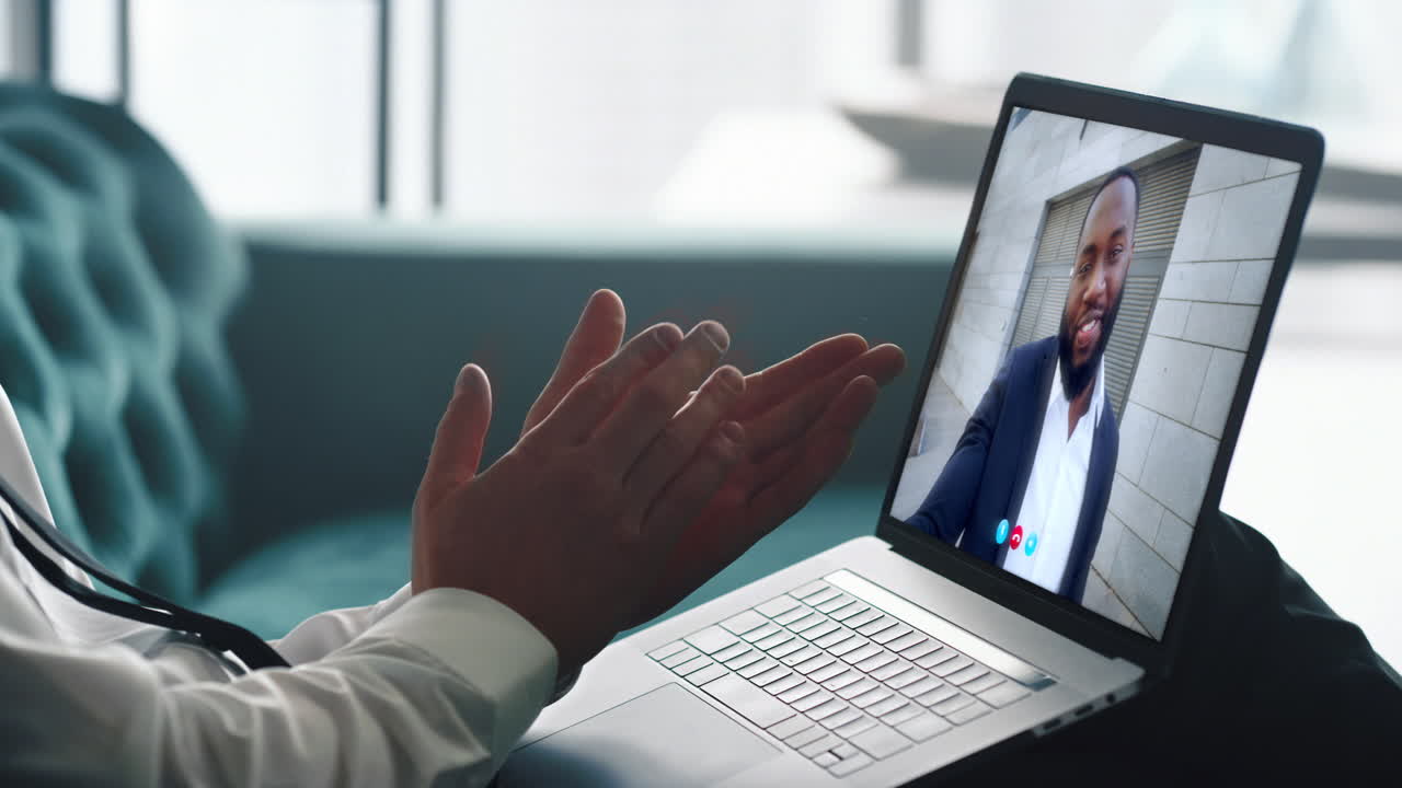 Entrenador de negocios sonriente haciendo una videollamada a un empresario desconocido en una oficina, primer plano