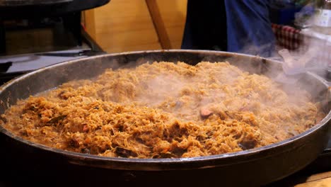 polish dish - bigos. a large portion of cabbage with sausage cooking in a pot outdoors