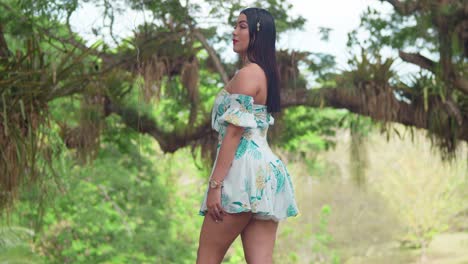 latina sexy en un parque tropical en un vestido corto en un día soleado