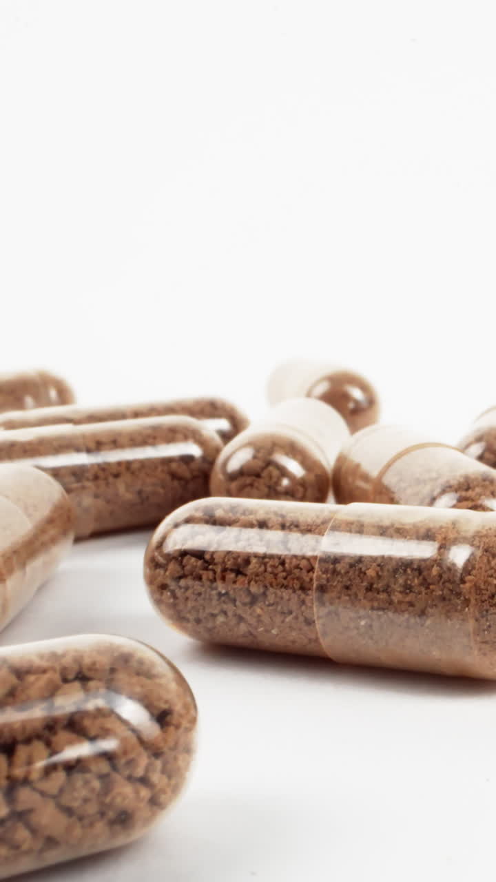 primer plano de cápsulas de suplementos a base de hierbas esparcidas sobre un fondo blanco brillante