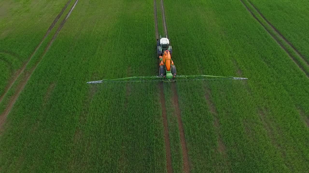 Irrorazione di pesticidi e fertilizzanti sul campo, vista aerea con trattore