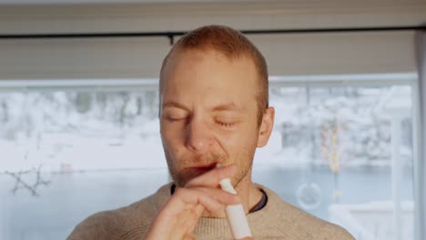 man administers nasal spray for congestion, portrait of caucasian 36 year old