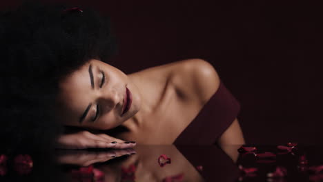 portrait beautiful african american woman relaxing rose petals falling on soft skin sensual female dreaming of intimate fantasy romance indulging desire in red valentines day concept