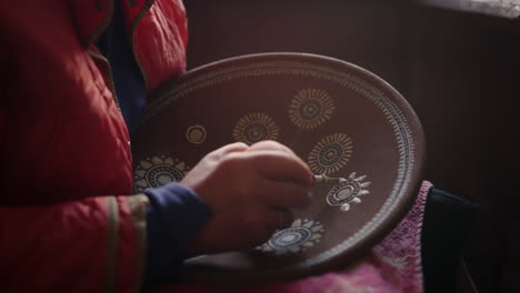 unknown woman making decoration in workshop. artist drawing ornament on plate