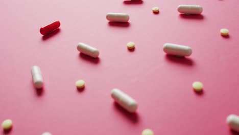 video de una variedad de píldoras dispuestas en fondo rosa con espacio para copiar