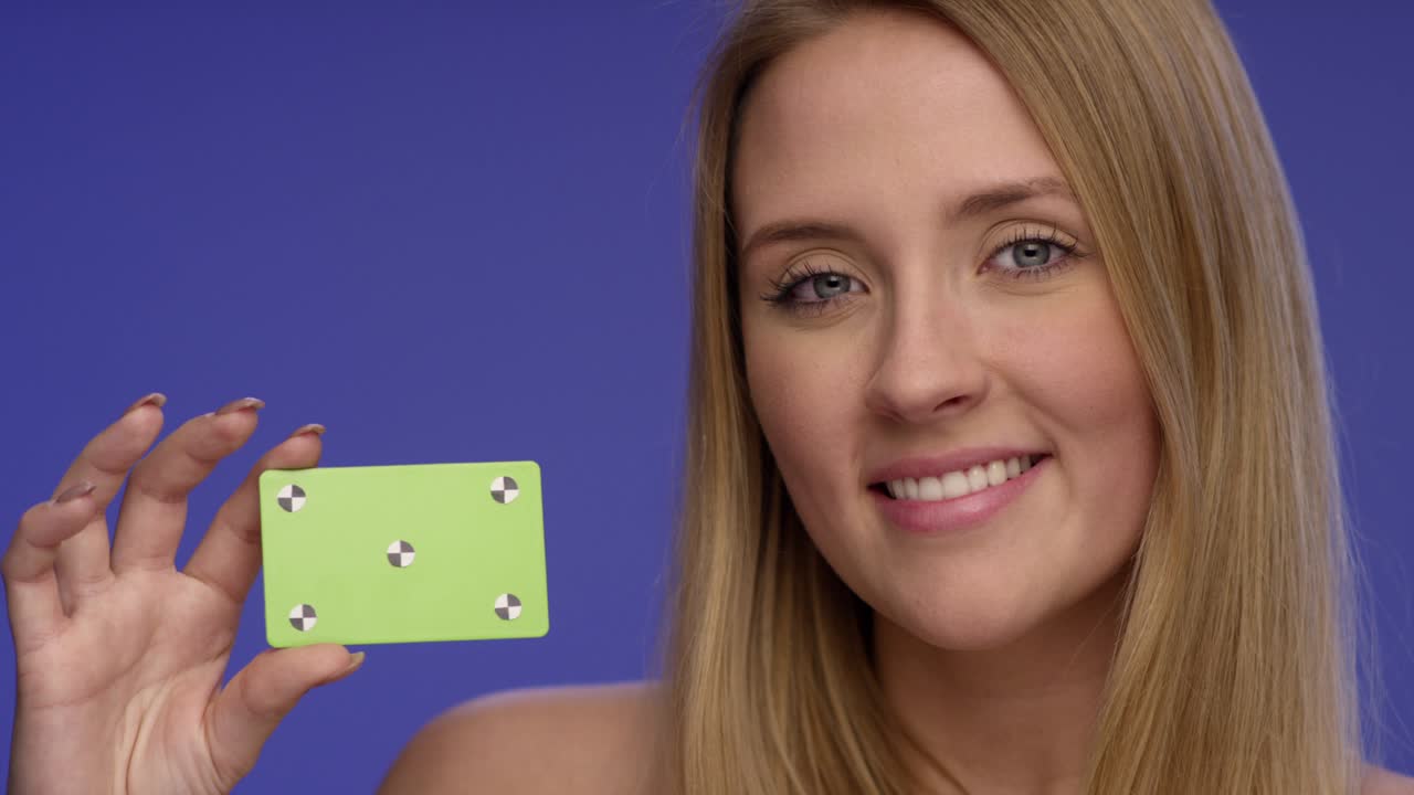 retrato cercano de una mujer hermosa mirando una tarjeta de crédito en blanco que está sosteniendo con una mano