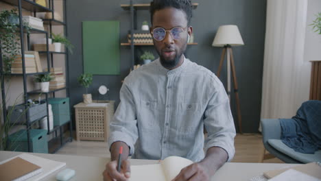 man taking notes during a virtual meeting