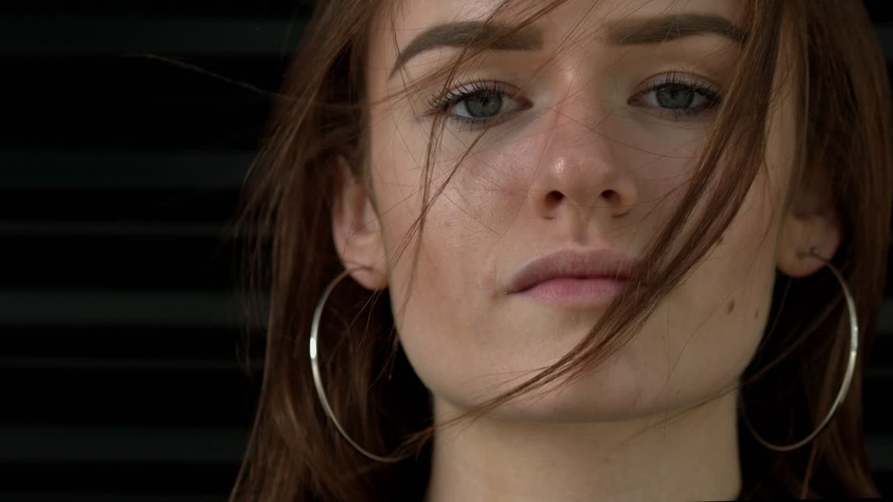 primer plano retrato de una mujer con cabello castaño, usando aretes grandes