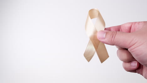 detail of male hand holding orange ribbon over white background