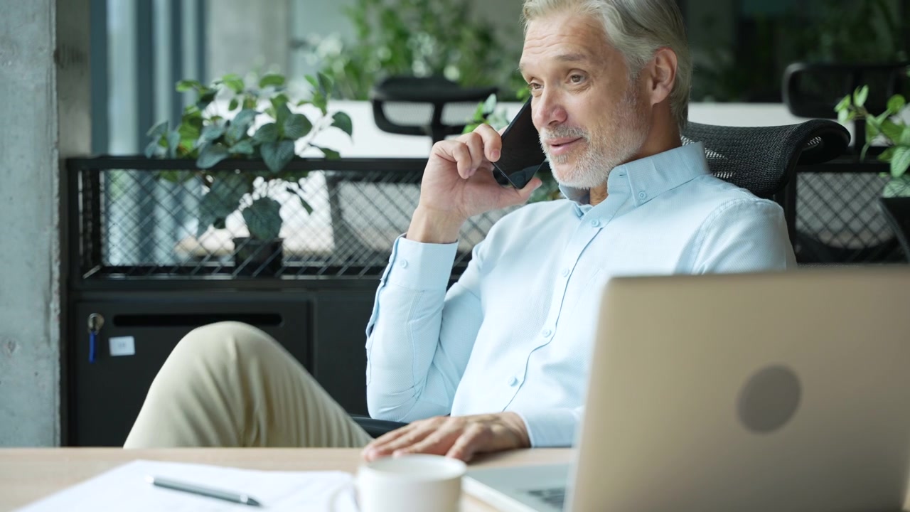 Uomo d'Affari Maturo che Parla allo Smartphone in un Ufficio Moderno