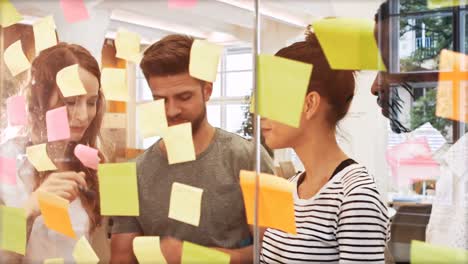 male and female business executives discussing over digital tablet while reading sticky notes