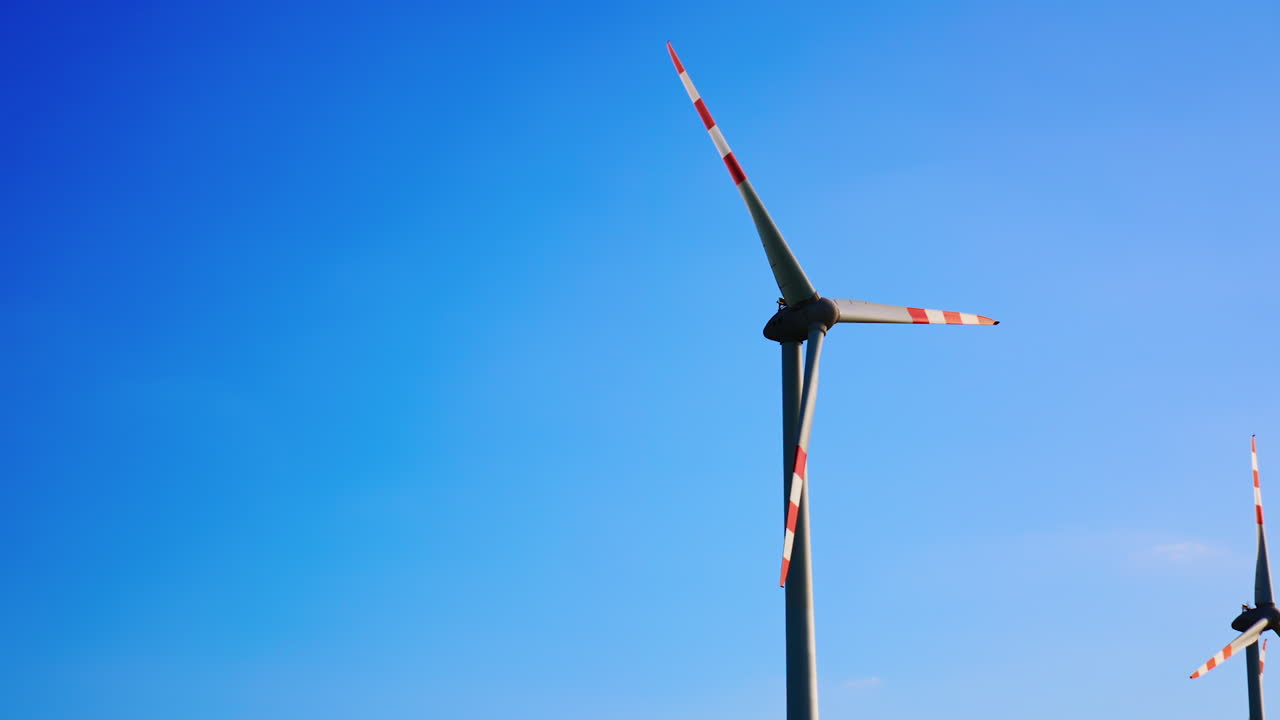 Wind turbines in blue sky. Wind turbines spin under a clear blue sky, harnessing renewable energy in an open landscape