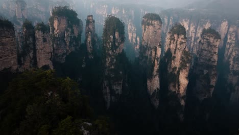 aerial view of towering forest-covered sandstone spires rising through mist in the otherworldly landscape of zhangjiajie national park