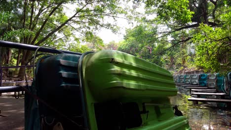 colorful pedal boats resting near the canal, surrounded by lush trees and dappled light