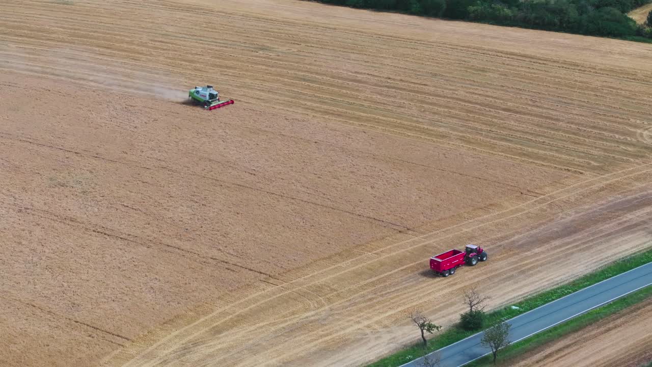 항공 - 수확 수확을 결합하고 트랙터와 화물 상자 곡물을 기다립니다