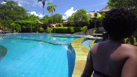two woman sitting along the pool at the luxury hotel resort and spa. relaxing on a hot sunny day wearing a two piece bikini. while having gun on vacation