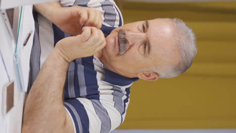 video vertical de un anciano trabajador de oficina en casa esperando nerviosamente en la computadora portátil.