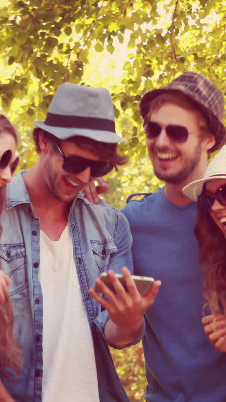 Amici felici che guardano foto su uno smartphone al parco