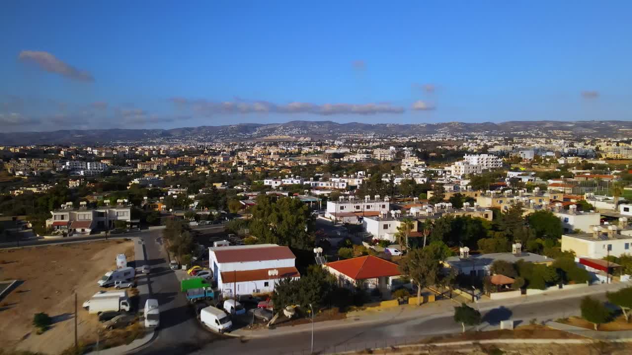 Aerial view of suburban city with dense housing, rocky cliffs, and clear blue sky in the background, capturing peaceful landscape and urban sprawl from high angle