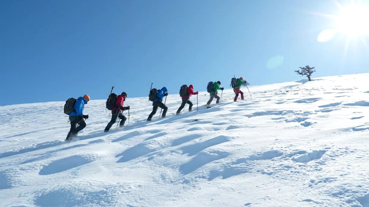 Squadra di trekking in montagna che attraversa un paesaggio innevato