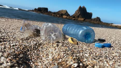 plastic bottles and debris scattered on a pebbled beach by the ocean shore