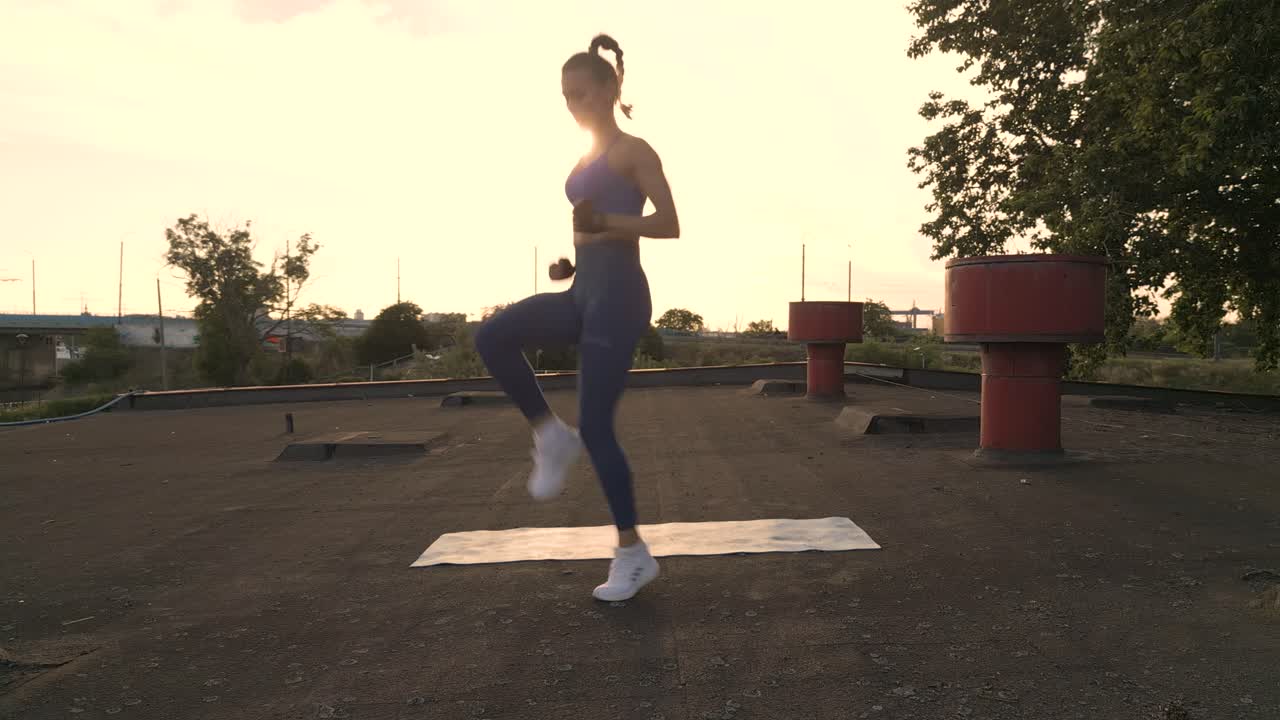 una mujer de fitness corre en el lugar, levantando sus rodillas altas cuando se pone el sol