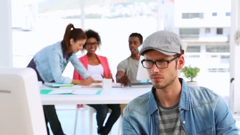 Designer working hard with colleagues talking behind him