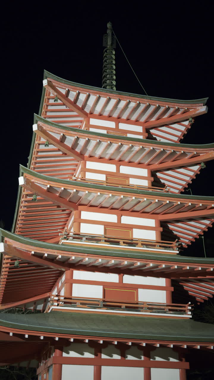 Chureito Pagoda illuminated at night, showcasing its unique architectural features against a dark sky. Vertical video